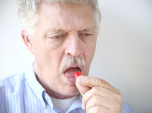 Older man taking a lozenge to help with dry mouth due to oral cancer
